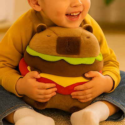 Un enfant souriant étreint une peluche capybara en forme de hamburger.