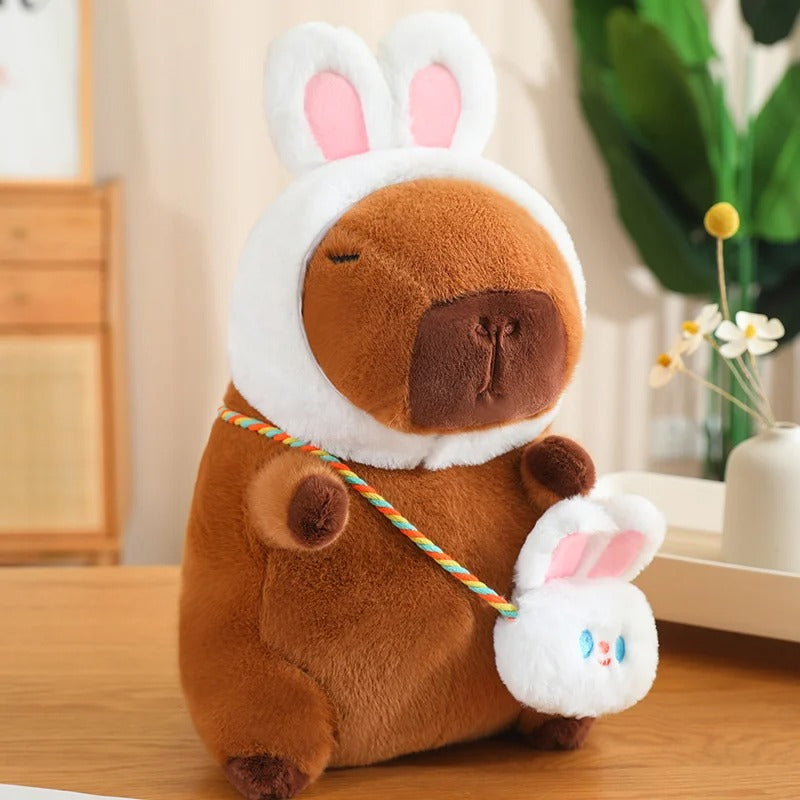 Peluche capybara adorable avec un déguisement de lapin blanc.