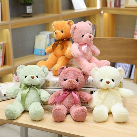 "Cinq ours en peluche colorés, doux et mignons, posés sur une table."