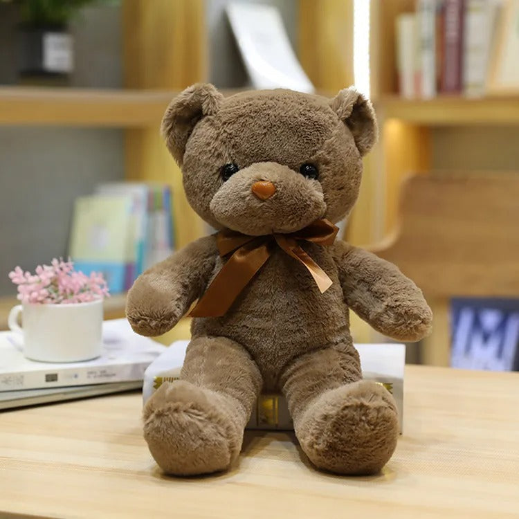 Adorable Ours en peluche brun assis, nĆud satinĂ©, fond flou.