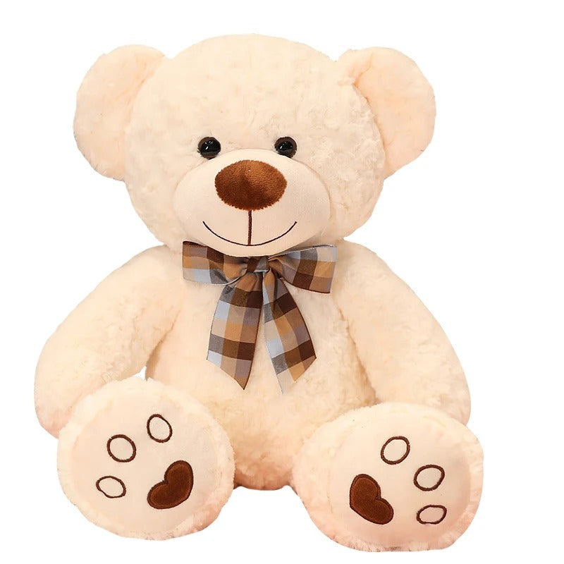 Un adorable ours en peluche crĂšme de 35cm avec un nĆud papillon Ă carreaux.