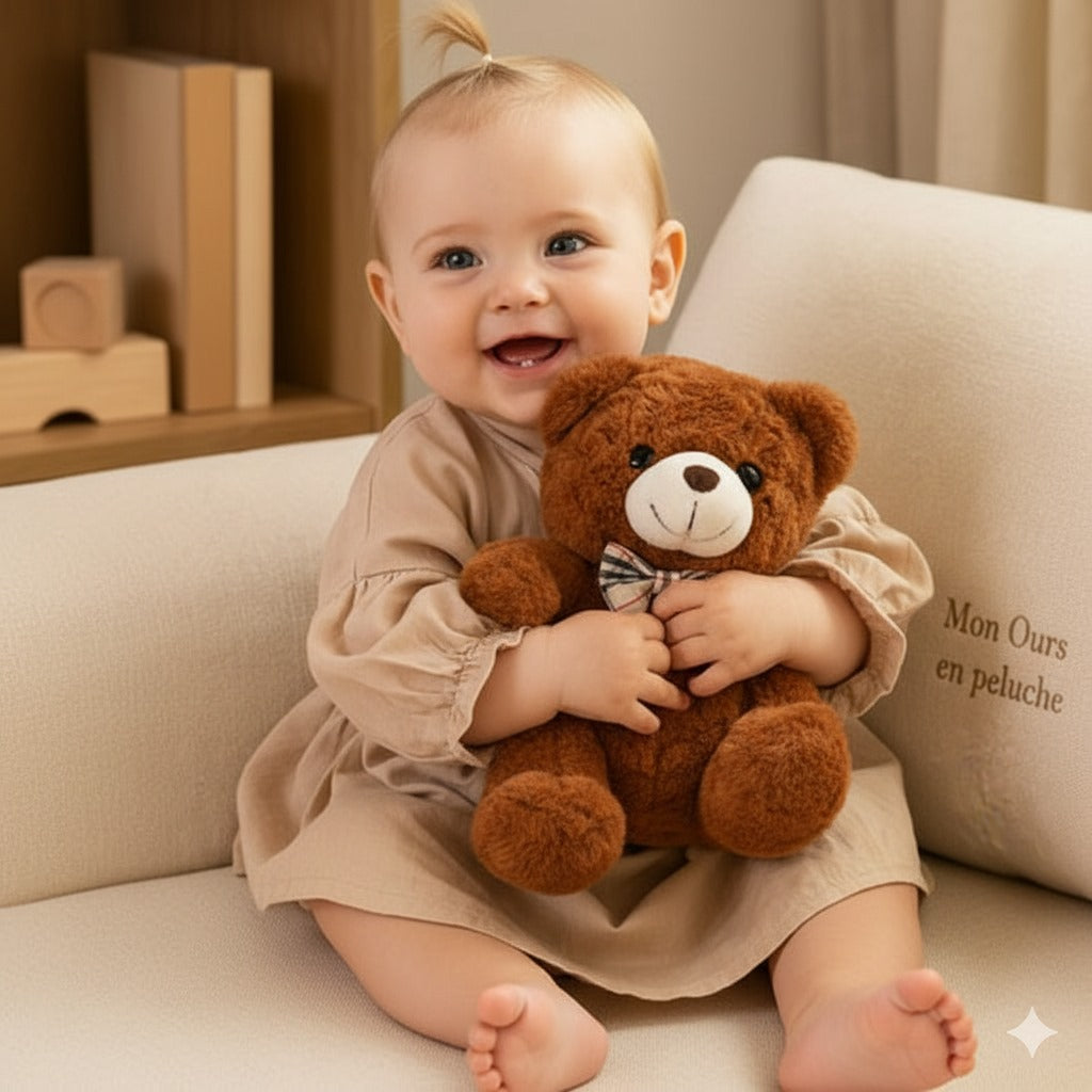 Bébé souriant, yeux bleus, serre son Ours en peluche marron.