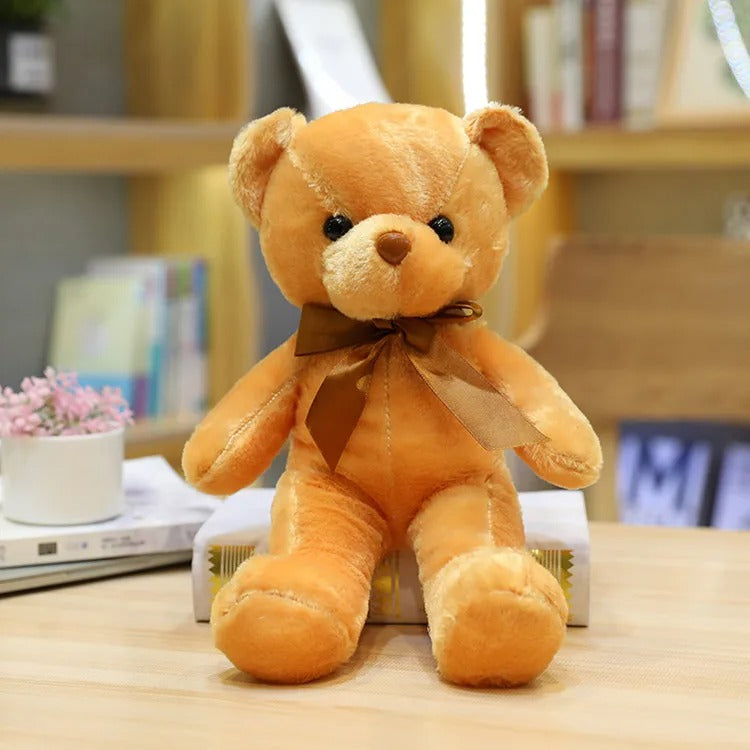 Adorable ours en peluche brun clair avec un nĆud marron assis.