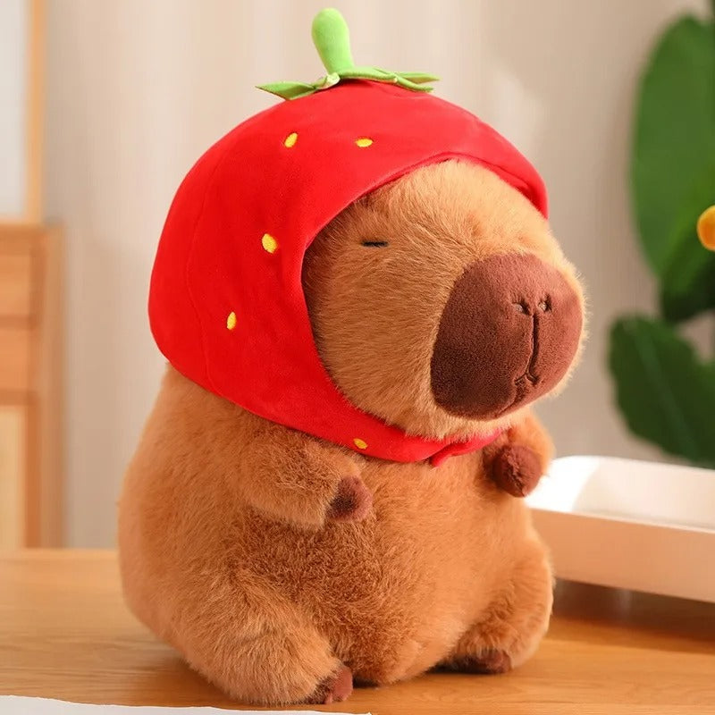 Adorable peluche capybara portant un bonnet fraise rouge, mignon et doux.