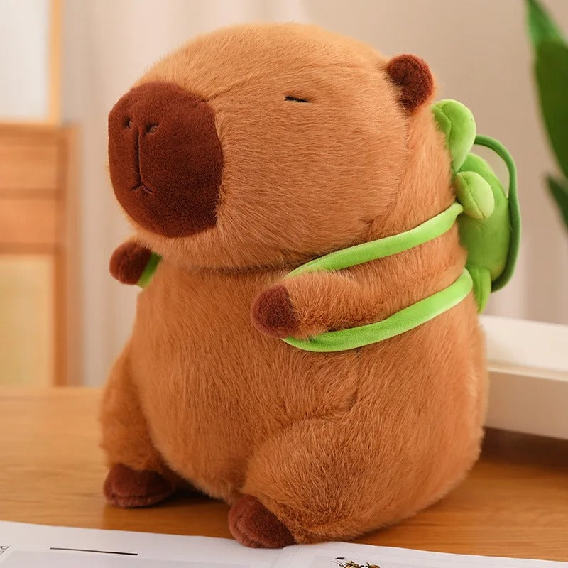 Adorable peluche capybara marron avec mini sac Ă dos vert.