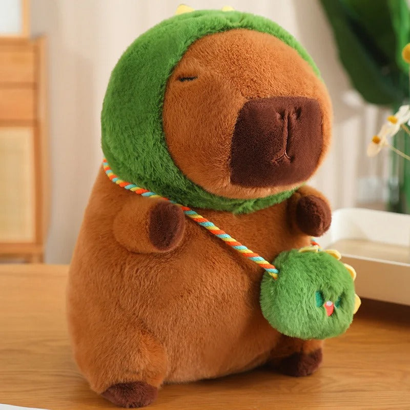 Peluche capybara adorable, marron, avec capuche verte et petit sac.