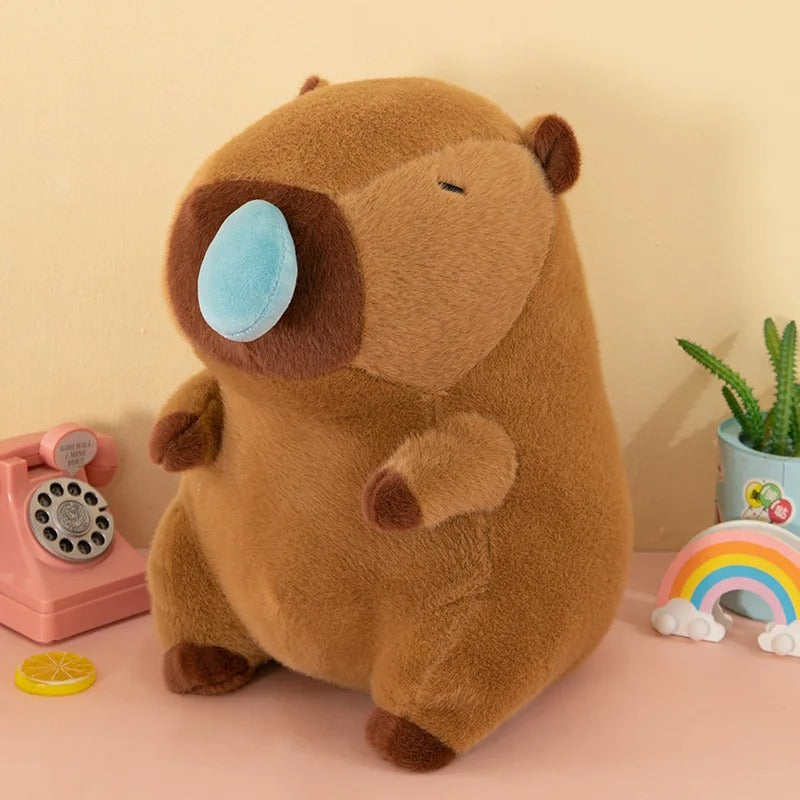 Adorable peluche capybara marron, nez bleu pastel, assis, jouet pour enfant.