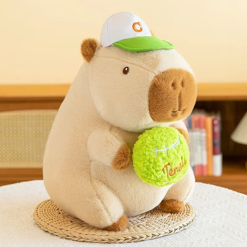 Peluche capybara adorable, casquette et balle de tennis, parfaite décoration douce.
