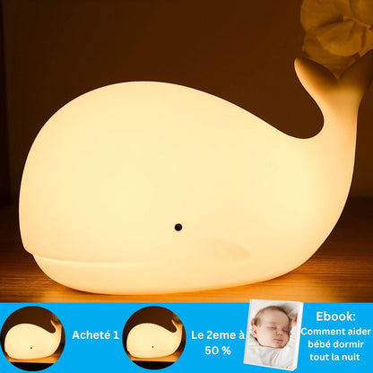Une veilleuse baleine lumineuse Marine-Light™ de Petitsbeautes sur bois crée une ambiance marine. En dessous, une bannière montre un bébé endormi et propose une réduction à lachat dun deuxième article. Le texte en français mentionne un livre électronique sur laide au sommeil des bébés avec des matériaux sécuritaires.