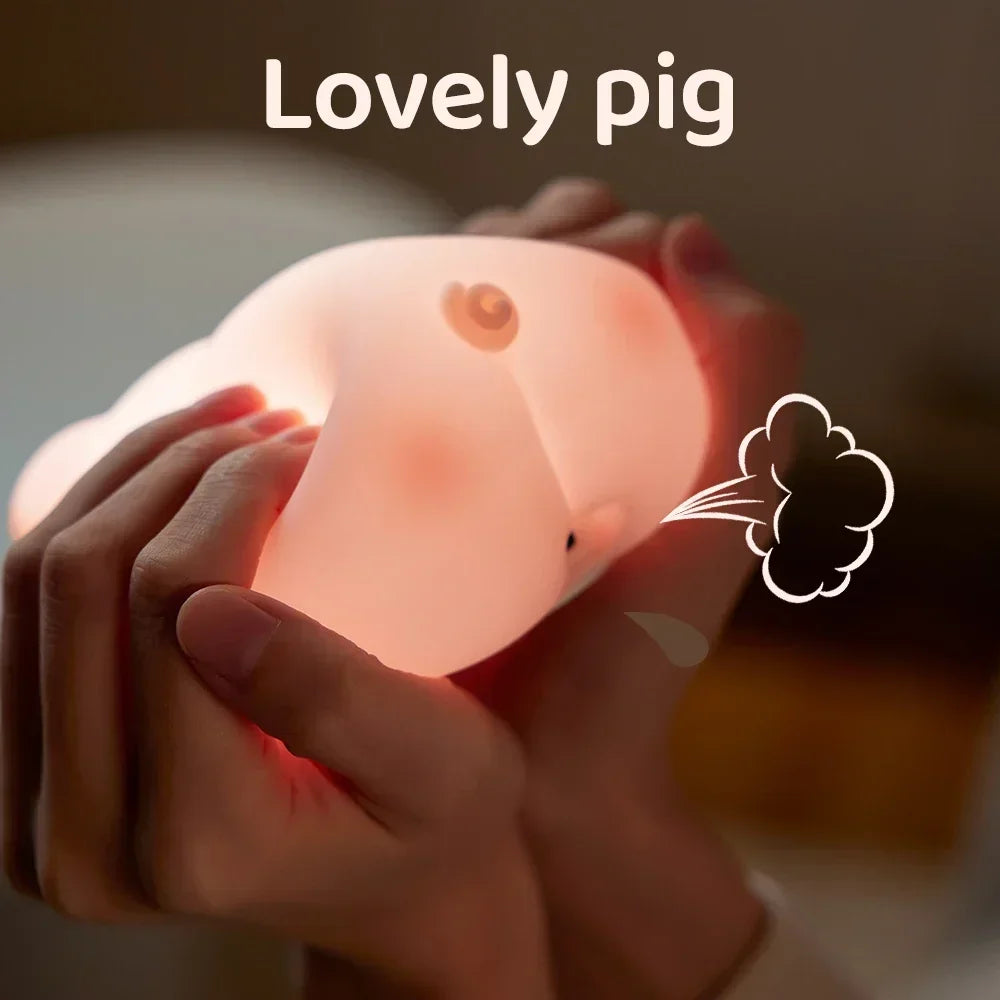 Gros plan des mains qui serrent un cochon en peluche Porcin™ doux et lumineux, suggérant une bouffée d'air avec une illustration de petit nuage. Les mots « Lovely pig » en haut soulignent son charme de veilleuse bébé.