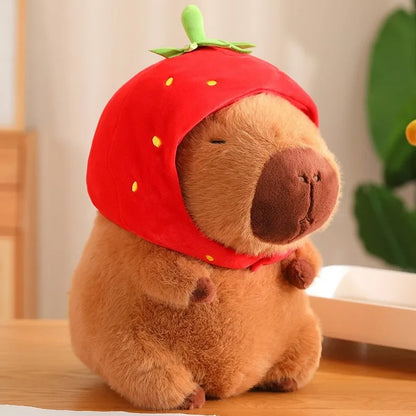 Adorable peluche capybara portant un bonnet fraise rouge, mignon et doux.